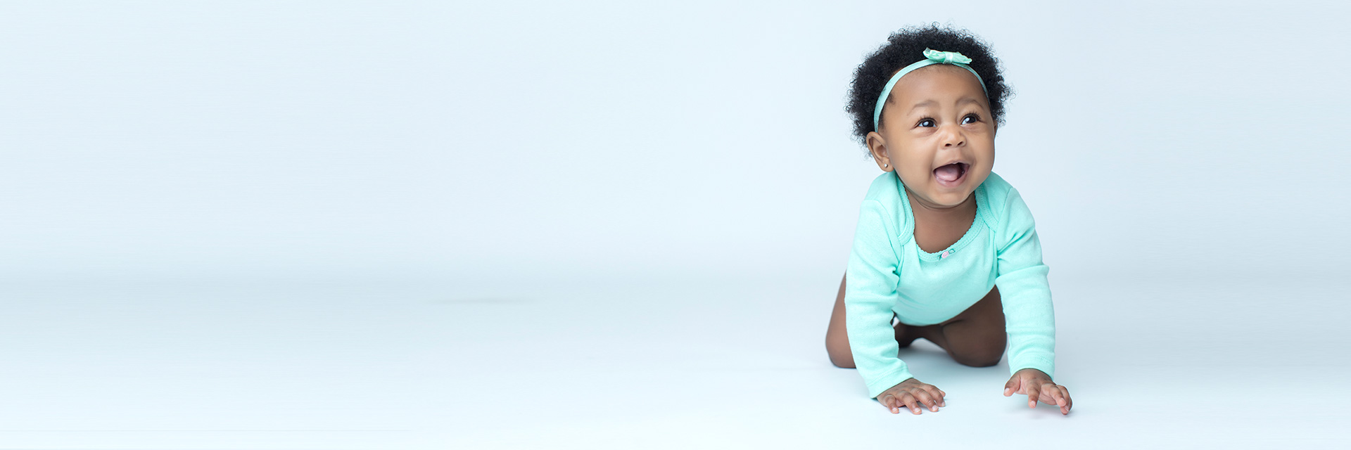 African American Baby in Teal Crawling on Floor