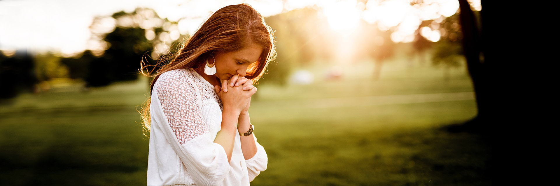 Woman Clasping Hands and Praying Outdoors