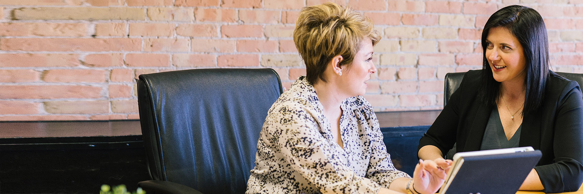 Two women looking at a tablet computer talking