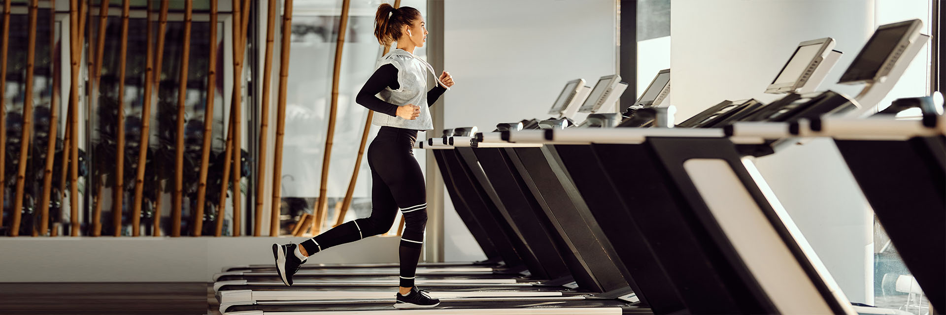 Woman running in sweats on treadmill in gym