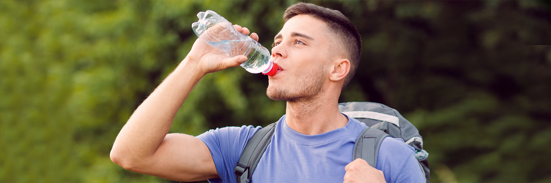Man drinking from a water bottle outdoors